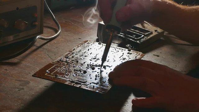 the old man repairs the chip radio technician smoke is coming repair soldering iron. Engineer or technician repair electronic lifestyle circuit board with soldering iron. man repair chips concept