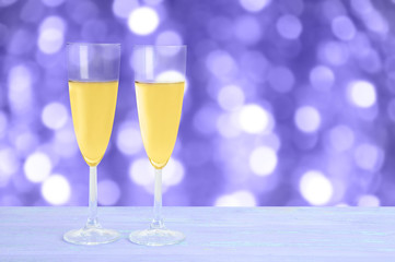 Two glasses with champagne on a wooden blue background. Blurred background, bokeh.