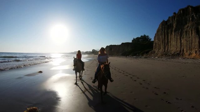 Riding horses on beach at sunset, slow motion