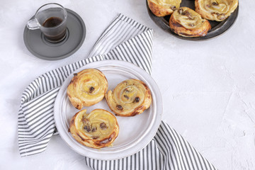 French breakfast concept - pain aux raisins, coffee, striped crumpled napkin.