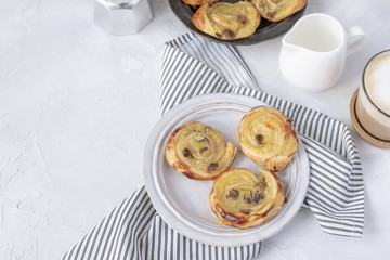 French breakfast - pain aux raisins, cappuccino, milk pitcher, coffe maker. Flat lay.