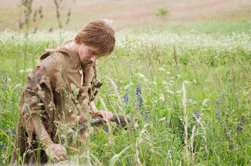 young man dressed as a medieval peasant from burlap in a field