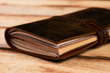 Old vintage leather book on wooden background. Handmade paper diary notebook in brown leather cover