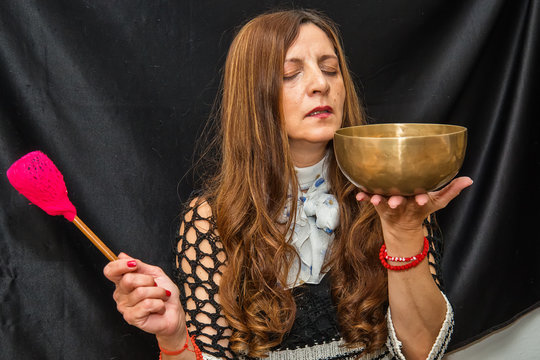 Woman playing a singing bowls also known as Tibetan Singing Bowls, Himalayan bowls. Tibetan Singing Bowls Treatment. Tibetan sound massage.