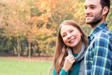 young couple of lovers in park. smiling woman affectionately holding to the man in autumn.