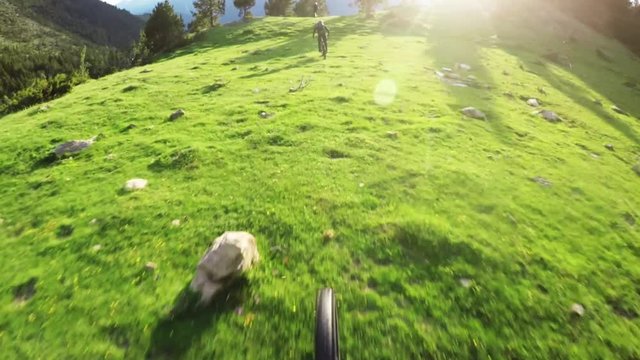 Slow motion POV, mountain bikers in sunny field