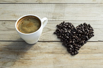 Cup of coffee and coffee beans on wooden background.