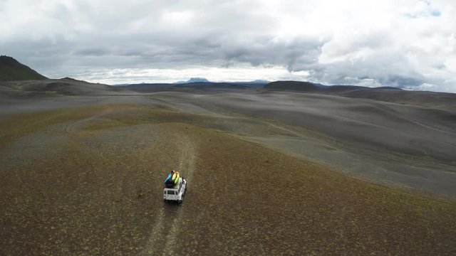 Car drives past rural mountains in Iceland, aerial