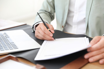 Male notary signing document at table in office, closeup