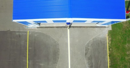 4k top view of man taking single engine airplane out of hangar ready to fly. Pilot moving plane out of airshed shed view from above. Tourism vacation aviation small business vehicle repair trip