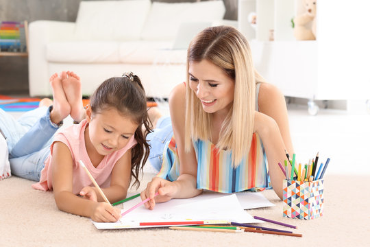 Beautiful mother drawing with cute daughter at home