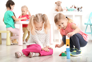 Cute little children playing with blocks in kindergarten