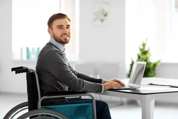 Young man in wheelchair at workplace