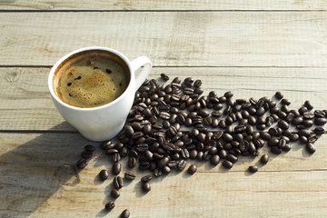 Cup of coffee and coffee beans on wooden background.