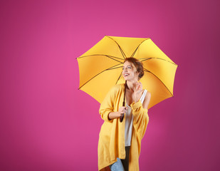 Woman with yellow umbrella on color background. Space for text