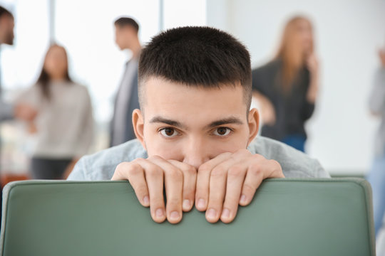 Man hiding behind chair during group therapy, indoors