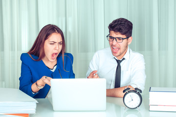 Angry woman and man with laptop looking at it screaming