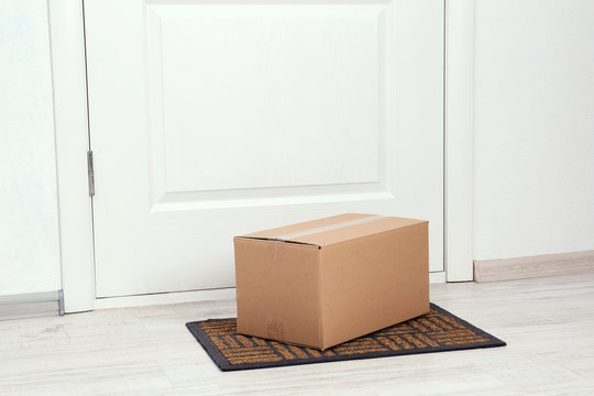 Cardboard box on floor near apartment entrance. Mockup for design