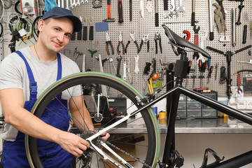 Professional mechanic repairing bicycle in modern workshop