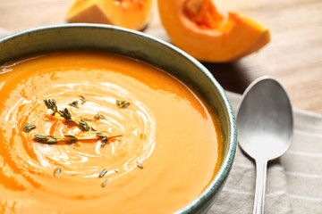 Delicious pumpkin cream soup with thyme in bowl on table, closeup