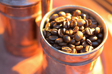 close up coffee beans  to in a copper container on a dark background