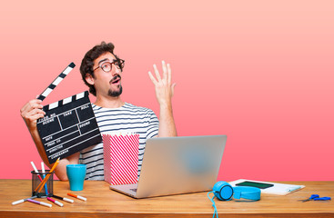 young crazy graphic designer on a desk with a laptop and with a cinema clapper