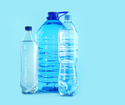 Different plastic bottles with pure water on color background. Space for text