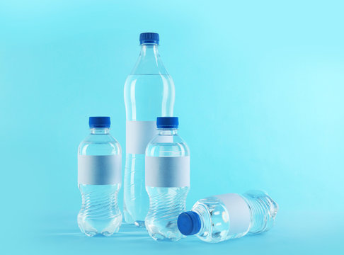 Different bottles of pure water with blank tags on color background