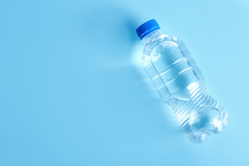 Bottle of water on color background, top view. Space for text