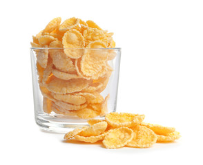 Glass with crispy cornflakes on white background
