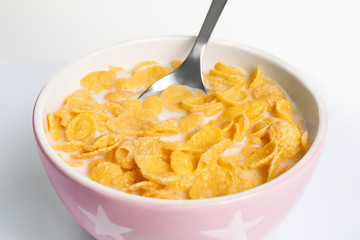 Bowl with crispy cornflakes on white background