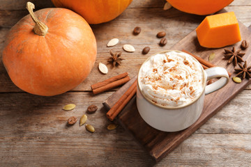 Cup with tasty pumpkin spice latte on wooden table