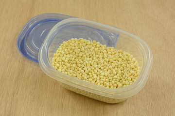 Raw uncooked Israeli couscous or ptitim pasta in plastic storage container