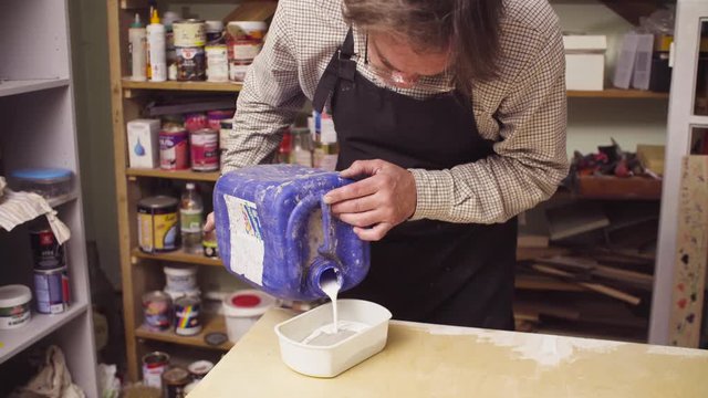 Senior artisan mixing cement in a small plastic box