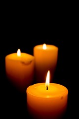 Fototapeta na wymiar Close-Up of Three Lit Candles on Black Background