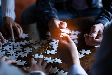 Hands holding piece of blank jigsaw puzzle on black background for teamwork workplace success and strategy concept.