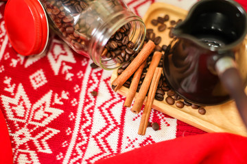 Fototapeta na wymiar Close up image of Coffee beans, cinnamon, turk on red knitwear background. Christmas evening background