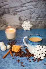 coffee cup with cinnamon sticks coffee beans and white christmas decor on blue background. Winter coffee shop background