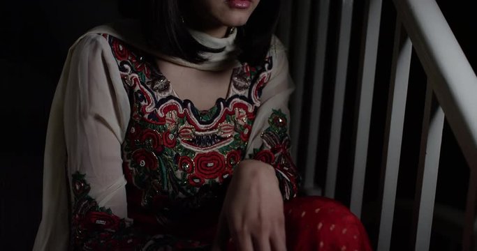 4K Depressed South Asian woman sitting alone on staircase, staring into darkness. Slow motion.