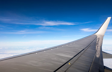Fototapeta na wymiar Wing of the plane on blue sky background. View of plane wing and sky from airplane window. Wing airplane over blue sky