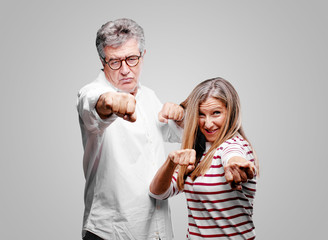 senior cool husband and wife with an angry, aggressive and menacing pose, ready for the fight,...