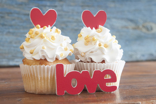 Cupcake and word Love on wooden table.