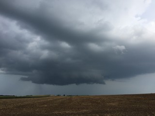 Dark cloud over empty farm field