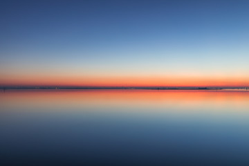 Mirroring sky in the water at twilight. Summer night picture of the surface of a calm lake...