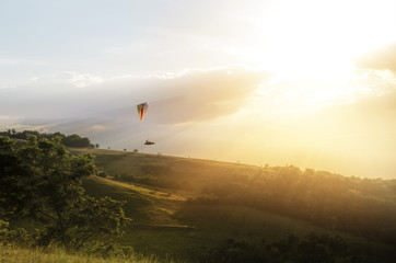 Paraglider pilot gliding , flying into the sunset 