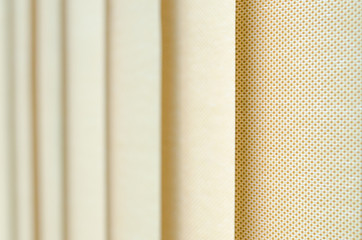 window curtain in closeup showing the texture in shades of beige. blurred background.