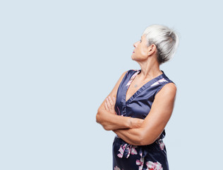 senior cool woman with a dissenting, serious, stern expression, with crossed arms in disapproval.