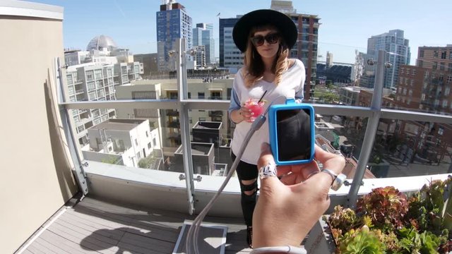 Woman drinks on urban rooftop, POV