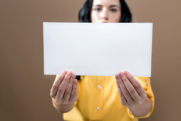 Young woman holding up a blank sign on a brown background