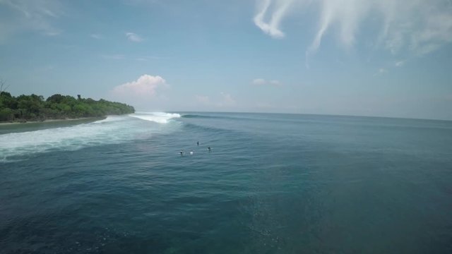 People surf off coast of Mentawai Island, wide aerial